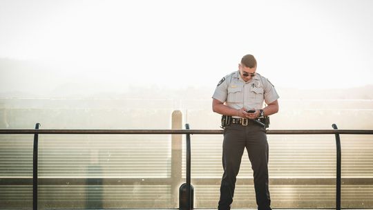 cop leaning on metal rail during a sunny day