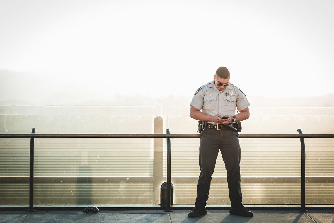 cop leaning on metal rail during a sunny day