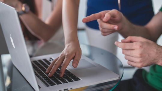 person touching and pointing MacBook Pro