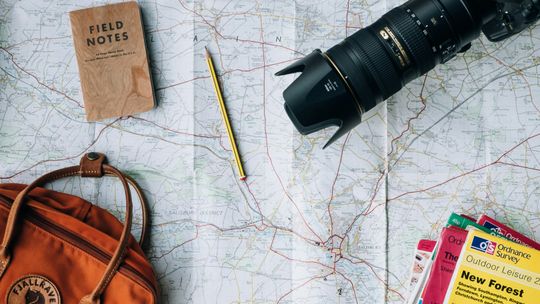 flat lay photography of camera, book, and bag